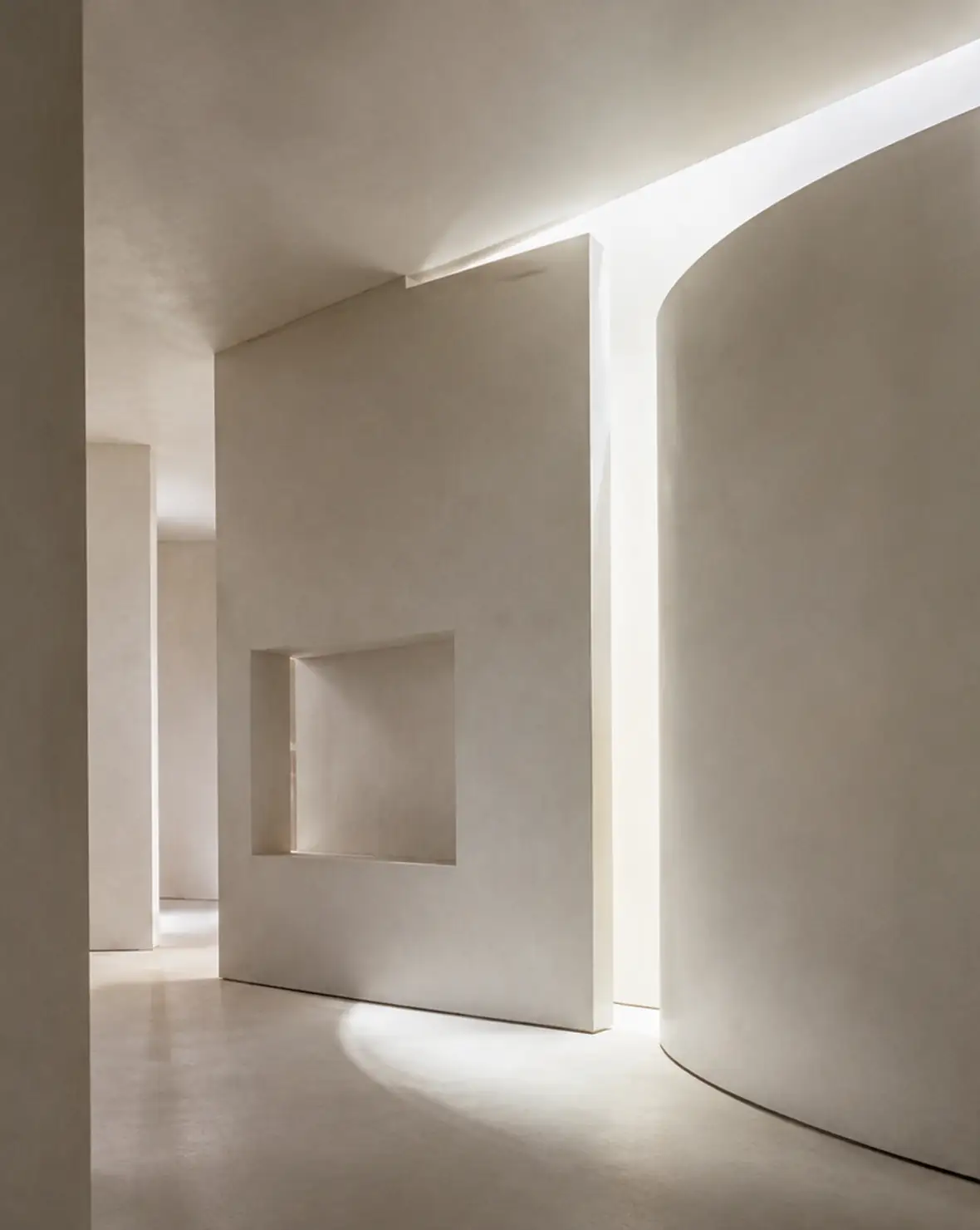 Planos blancos de yeso, un muro curvo y una ranura de luz componen un espacio sereno